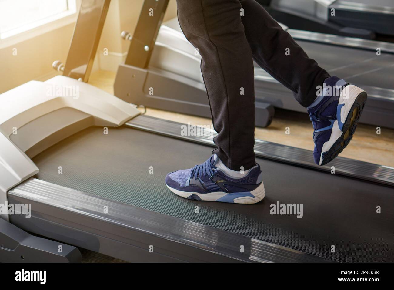 Closeup uomo gambe correre su un tapis roulant. Sicurezza durante l'esecuzione di esercizi cardio in scarpe sportive. Vista laterale Foto Stock