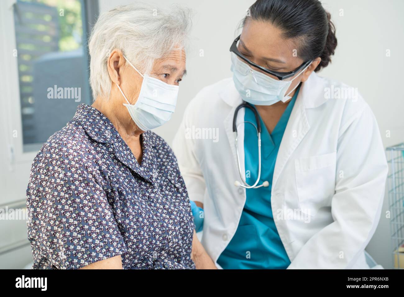 Medico asiatico indossare visiera e PPE tuta nuovo normale per controllare il paziente proteggere l'infezione di sicurezza Covid 19 Coronavirus focolaio in quarantena ospedale reparto infermieristico. Foto Stock