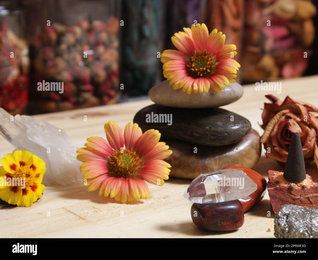 Cristallo di quarzo bilanciato su Bloodstone con fiori sullo sfondo DOF poco profondo Foto Stock