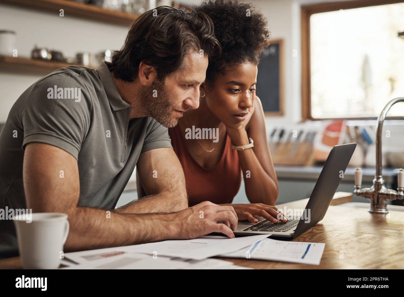 Proviamo questo collegamento. Scatto ritagliato di una coppia utilizzando il loro laptop e passando attraverso la documentazione a casa. Foto Stock