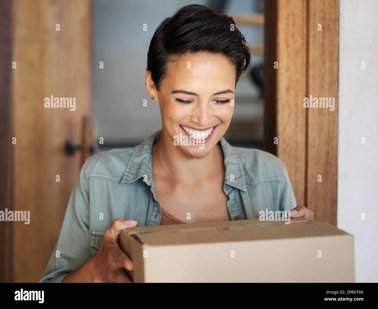 In tempo. Scatto di una giovane donna sorridente in piedi alla sua porta di fronte ricevendo un pacco da un corriere. Foto Stock