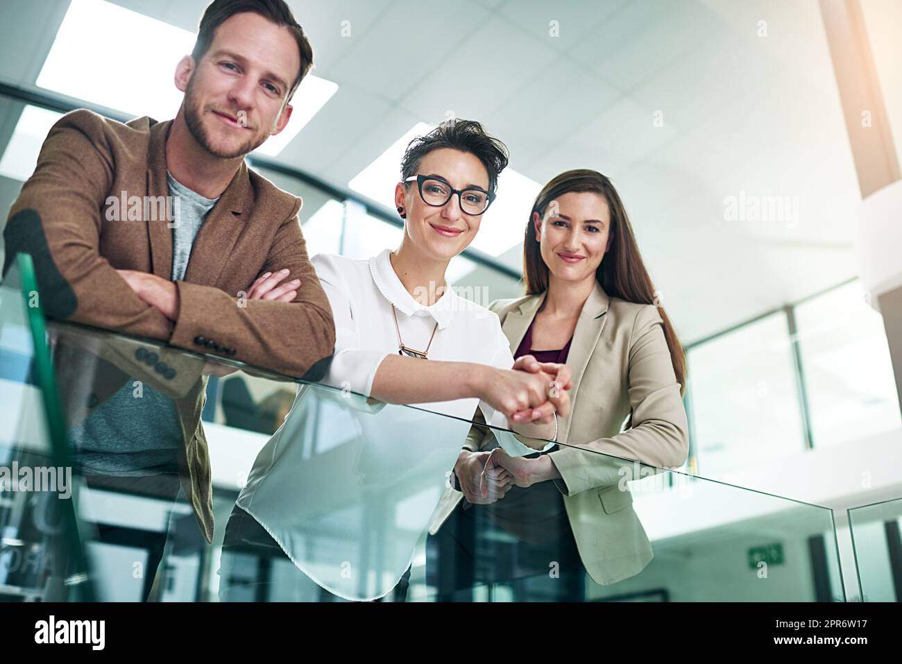 Weve ha ottenuto successo coperto. Ritratto di un gruppo di colleghi che si appoggiano su una ringhiera insieme in un grande ufficio moderno. Foto Stock