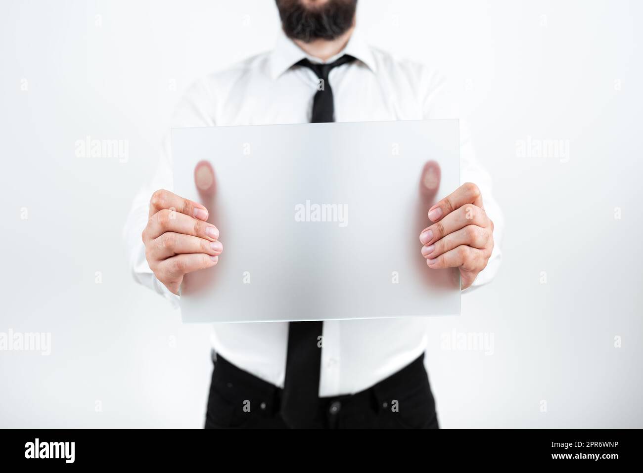 Uomo professionale che indossa la cravatta che tiene in mano un cartello vuoto e visualizza un messaggio importante. Uomo d'affari con la carta in mano che presenta strategie e informazioni per il progresso. Foto Stock