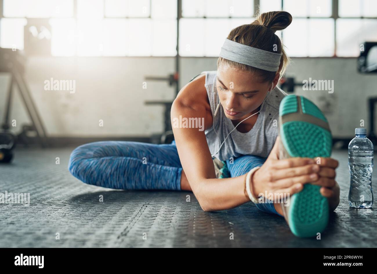 Aspira ad ispirare il fitness in se stessa ogni giorno. Scatto di una giovane donna attraente che si allunga in una palestra. Foto Stock