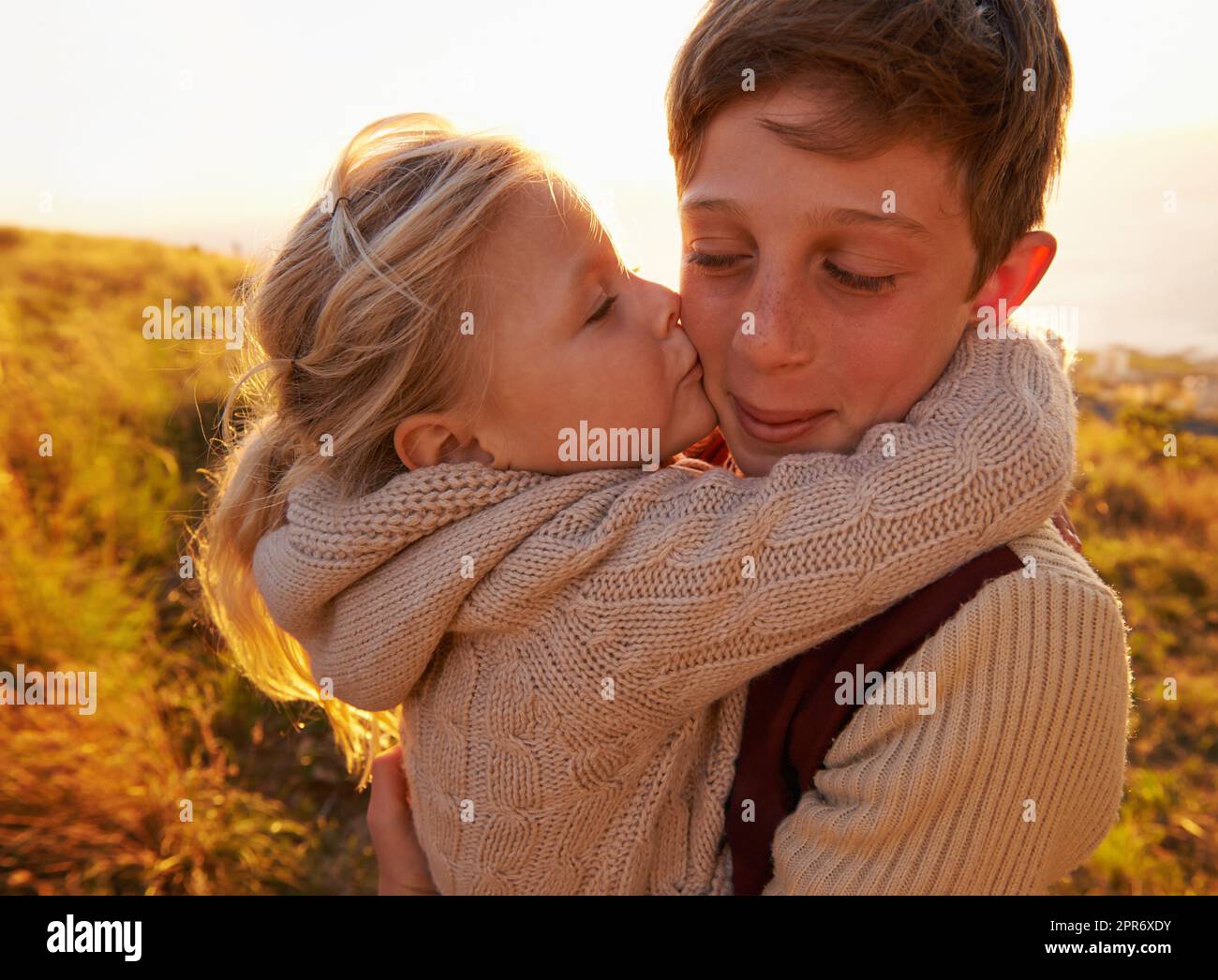 Un abbraccio per il suo eroe. Scatto corto di una bambina che dà a suo fratello un bacio sulla guancia mentre all'aperto. Foto Stock