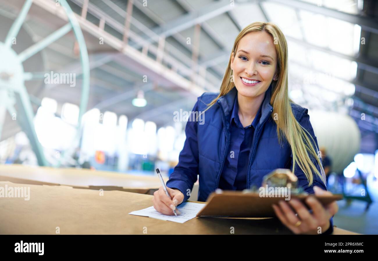 Il magazzino non poteva funzionare più liscio. Ritratto di un manager sorridente che legge i documenti mentre si trova in piedi sul pavimento della fabbrica. Foto Stock