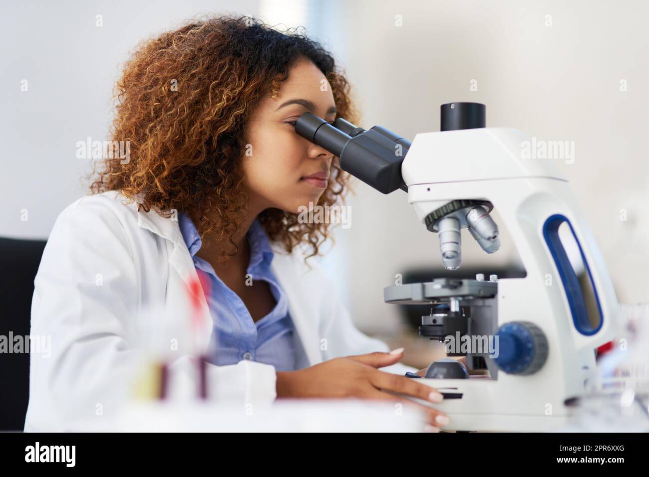 Analisi dei dati microscopici. Scatto corto di una giovane scienziata femminile che guarda al microscopio. Foto Stock