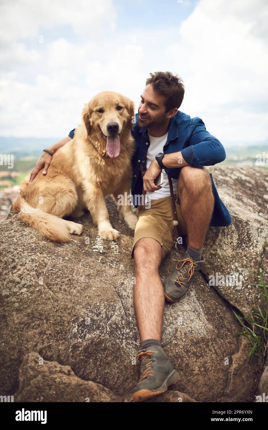 Bravo ragazzo, l'hai fatto. Scatto a tutta lunghezza di un bel giovane uomo e del suo cane che fa una pausa durante un'escursione in montagna. Foto Stock