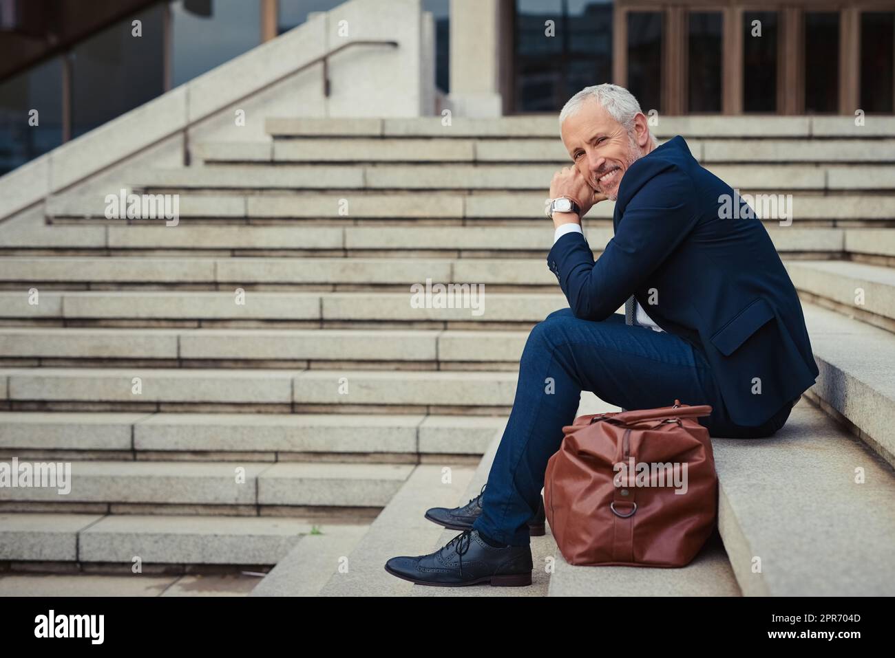 L'aria fresca impedisce alle mie idee di diventare obsolete. Ritratto di un uomo d'affari fiducioso seduto sulle scale fuori del suo edificio d'ufficio. Foto Stock