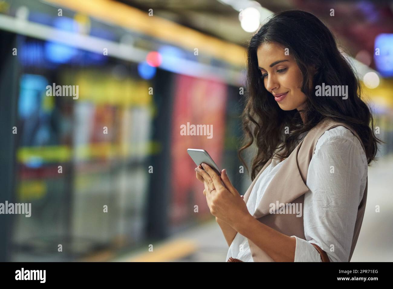 Connesso in movimento. Scatto corto di una giovane donna attraente usando un cellulare mentre si commuta con il treno. Foto Stock
