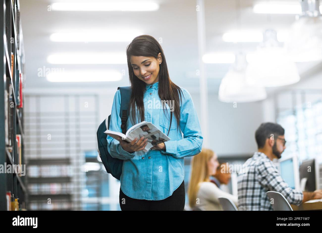 Lavorare sodo per ottenere un passaggio A+. Foto di uno studente universitario che legge un libro nella biblioteca del campus. Foto Stock