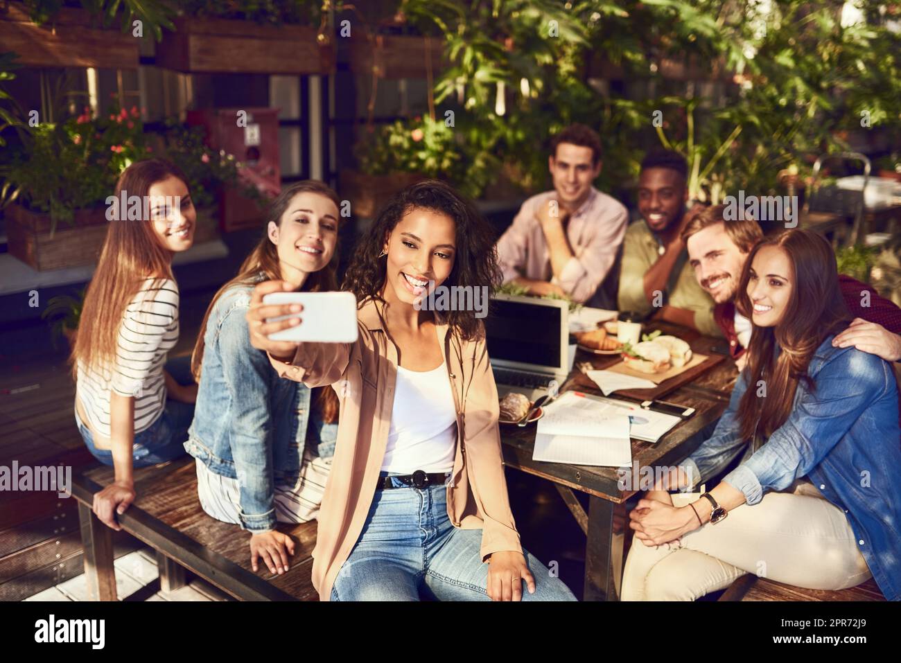 Im proprio qui per i selfie. Scatto corto di una giovane donna attraente che prende un selfie mentre fuori per pranzo con gli amici. Foto Stock