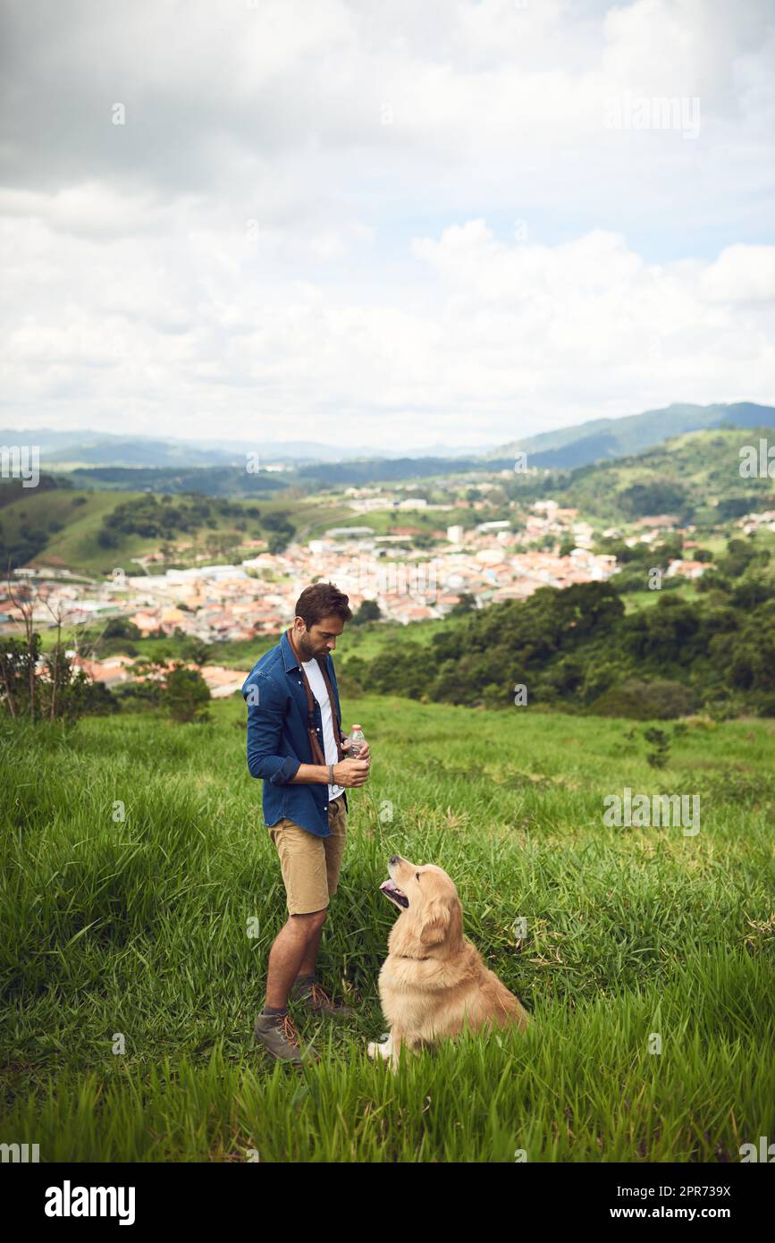 Non è richiesto alcun guinzaglio. Scatto a tutta lunghezza di un bel giovane uomo che prende il suo cane per una passeggiata in montagna. Foto Stock