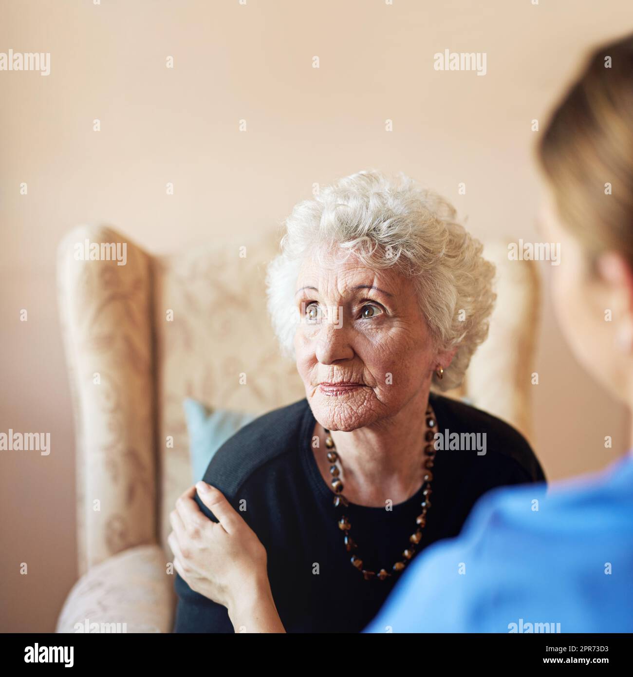 Pensieri dei giorni passati. Shot di un'infermiera che si prende cura di una donna anziana in una casa di cura. Foto Stock