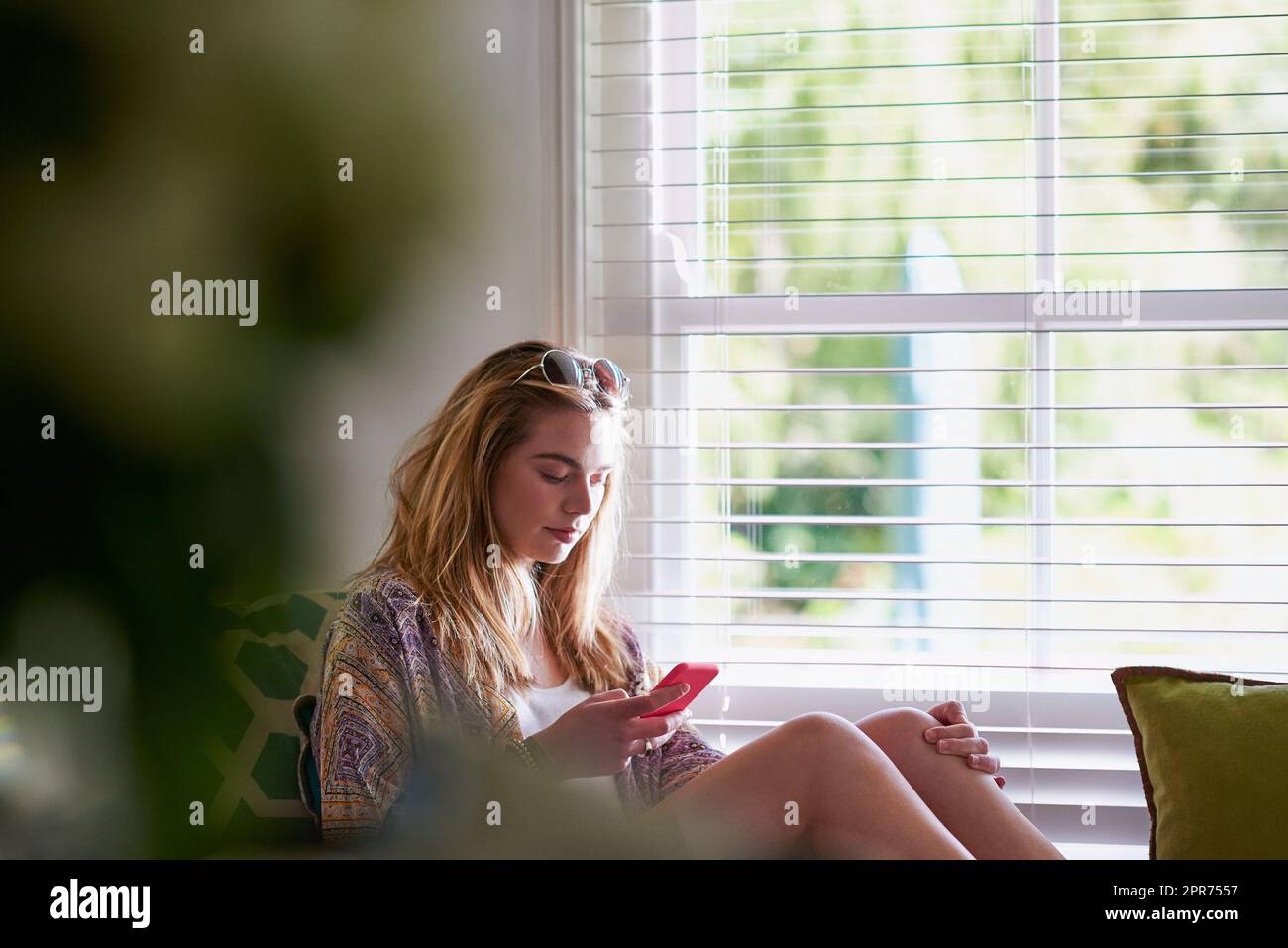 Così che cosa mi manca fuori sopra. Giovane ragazza hippie adolescente utilizzando il telefono cellulare alla finestra in stile americano casa. Foto Stock