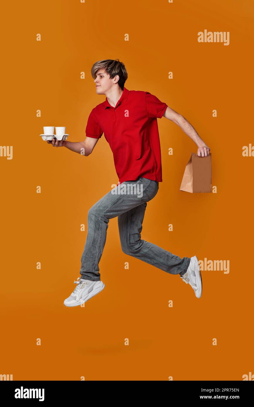 Uomo per la consegna in berretto rosso, t-shirt che tiene la scatola di cartone, caffè e salti Foto Stock