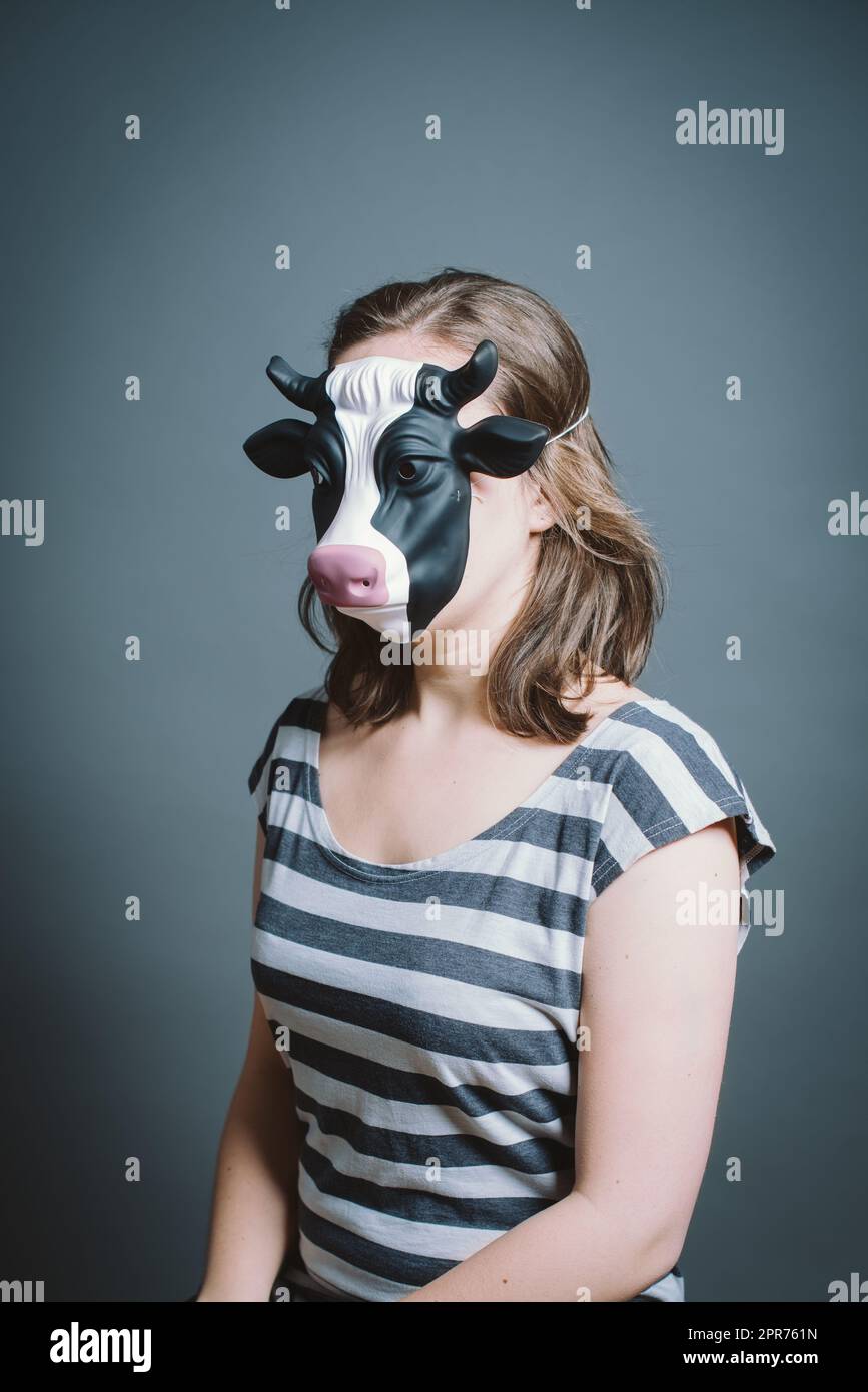 Giovane donna che indossa la maschera su sfondo grigio in studio. Giovane donna che indossa la maschera su sfondo grigio in studio. Foto Stock