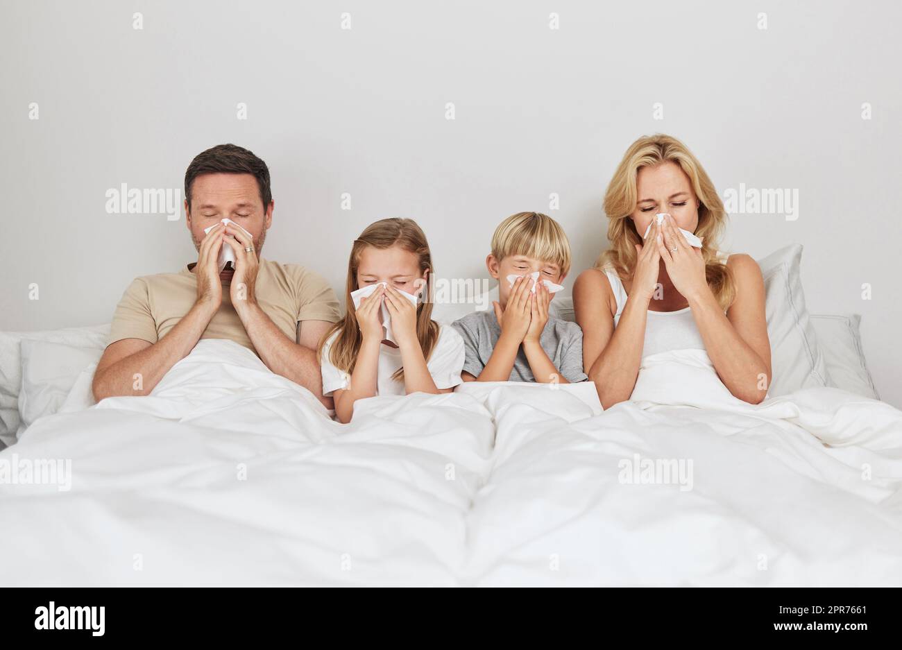 Attraverso spesso e sottile. Shot di una giovane famiglia che guarda ammalata a letto insieme. Foto Stock