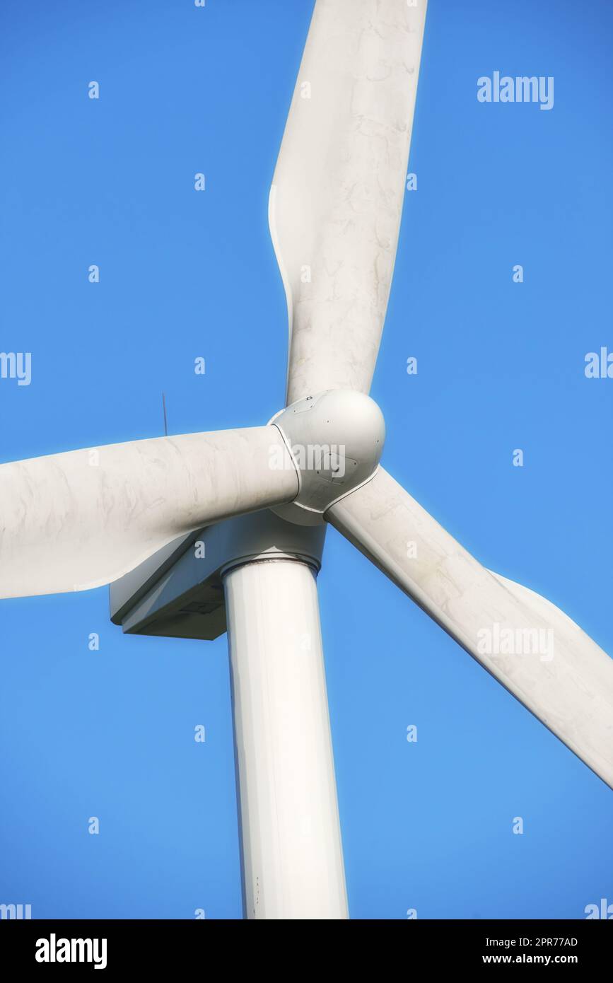 Energia rinnovabile e sostenibile generata da una moderna turbina eolica su uno sfondo blu all'esterno. Energia eolica o energia che genera elettricità pulita o energia meccanica utilizzando pale rotanti Foto Stock