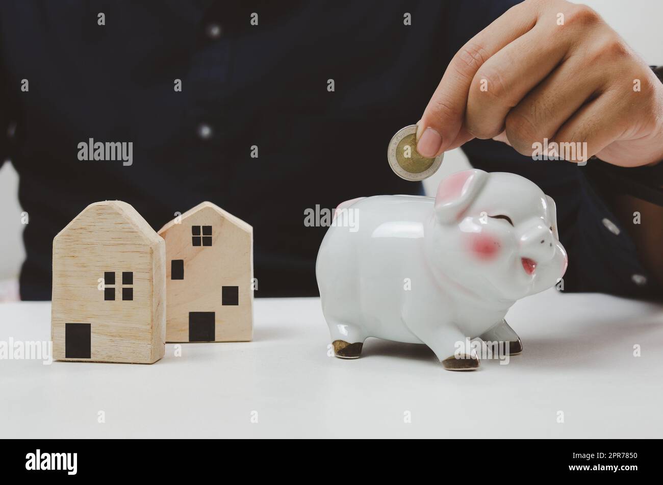 Mano che tiene la moneta di risparmio piggy banca finanza investimento prestito casa. Economia di affari concetto di proprietà immobiliare. Foto Stock
