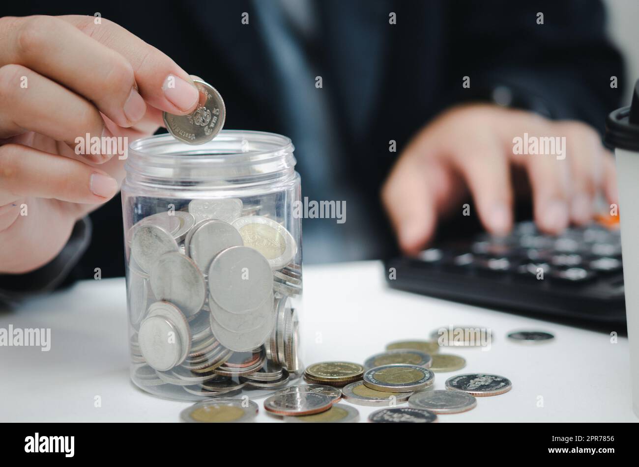 Pianificazione pensionistica o contabilità di investimento concetto aziendale finanza assicurazione tasse. Uomo d'affari che tiene in mano denaro risparmiando denaro in un barattolo e calcolatrice alla scrivania. Foto Stock