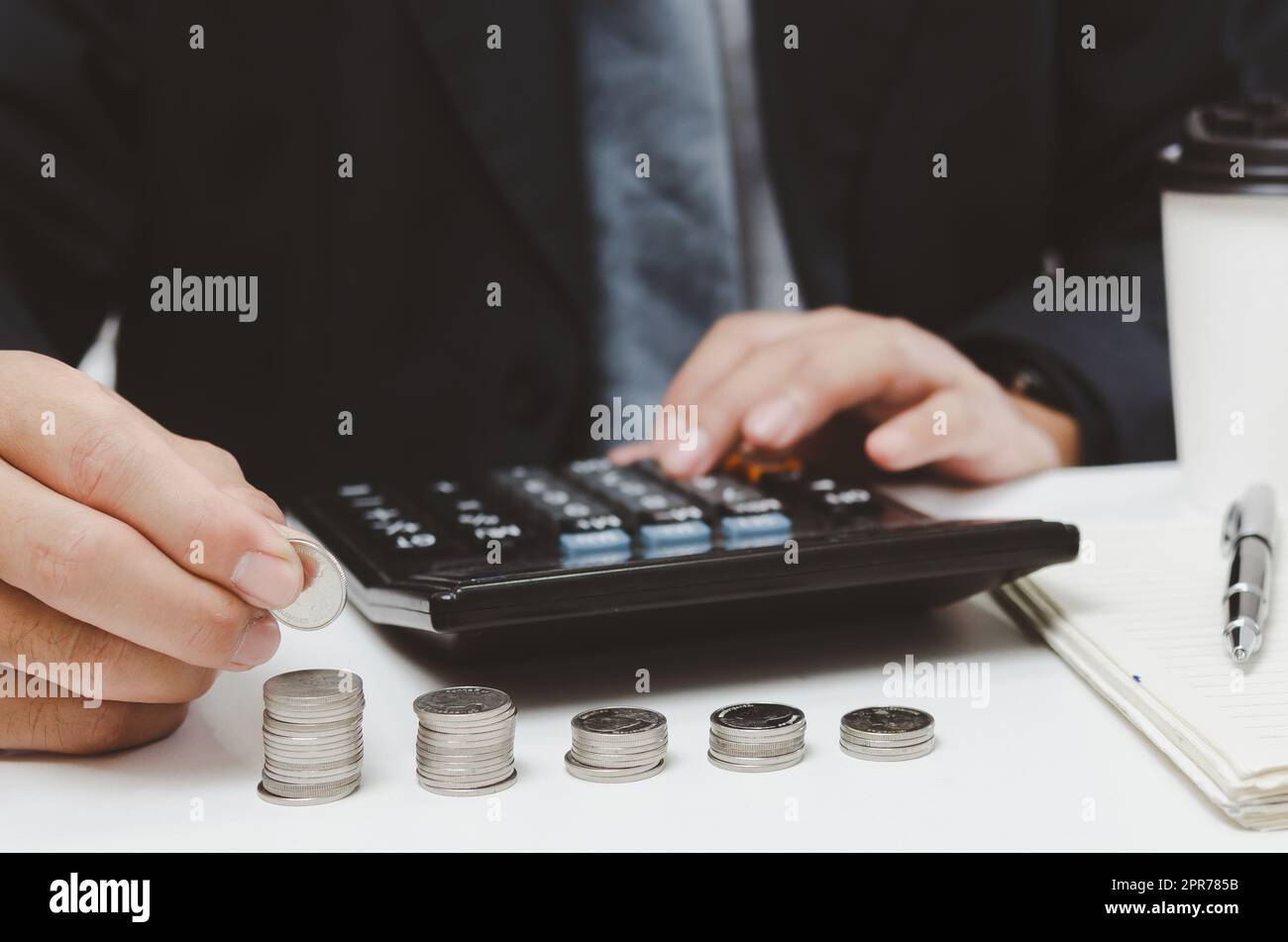 businessman mano che tiene moneta stack denaro e calcolatrice su desk.business finanza fiscale crescita investimento contabilità concetto di assicurazione Foto Stock