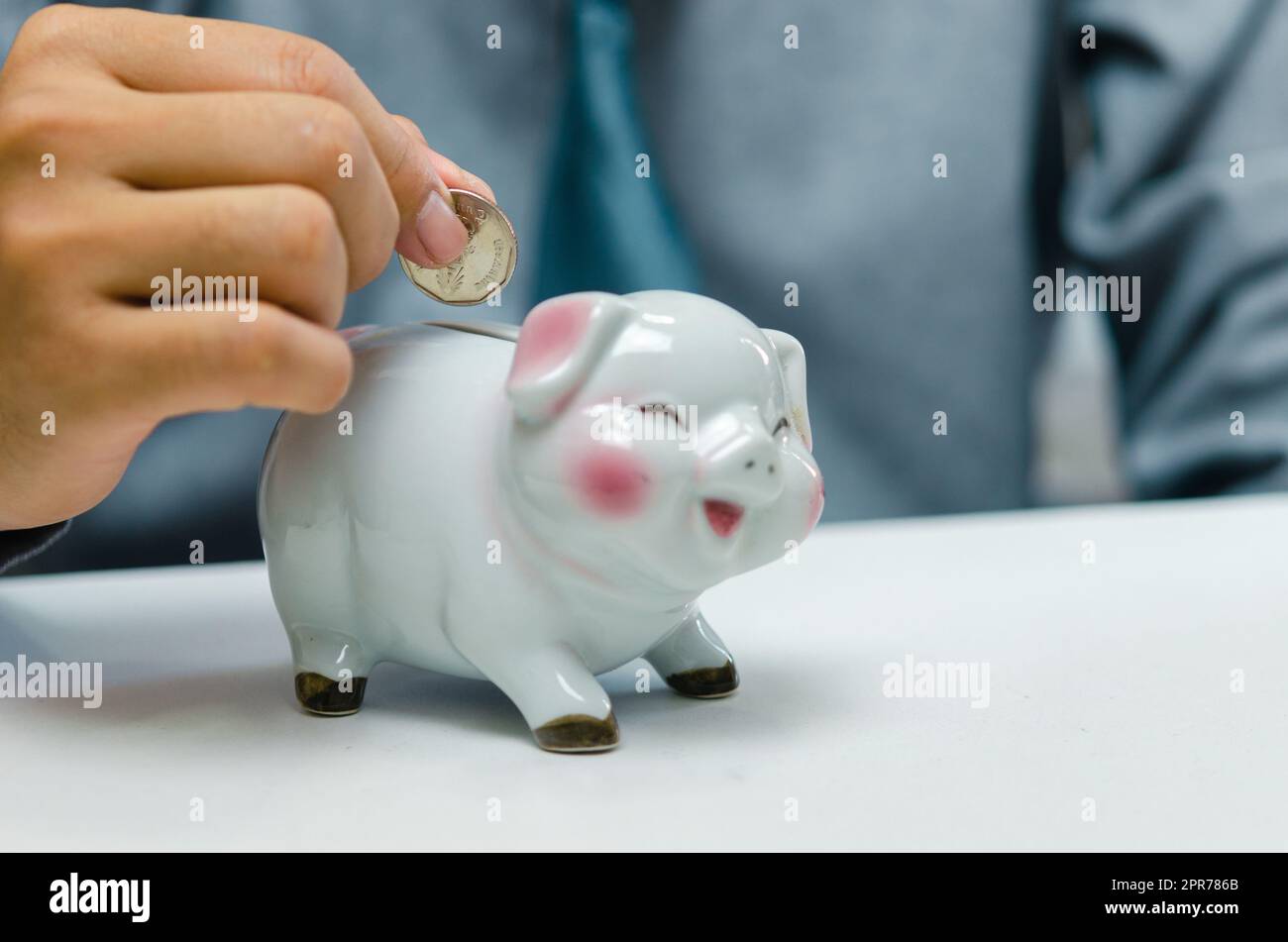 Uomo d'affari mano che detiene moneta risparmio di denaro piggybank sul tavolo.conto finanziario aziendale tassa di investimento economia assicurazione e piano pensione concetto. Foto Stock