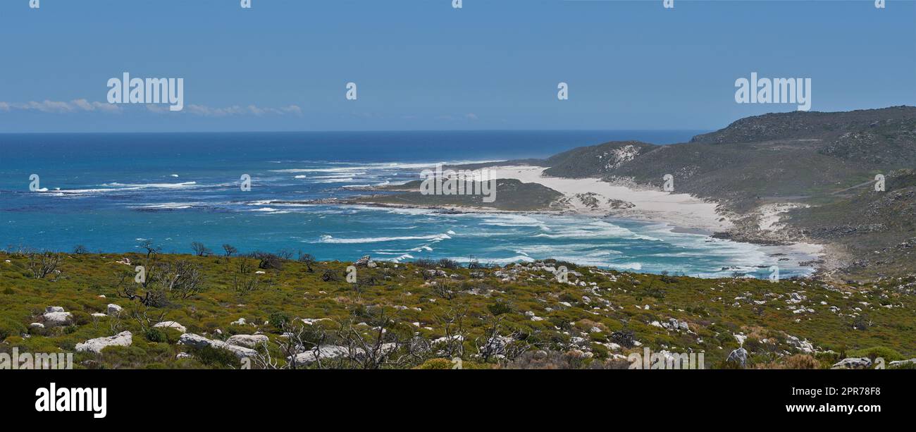 Copyspace in mare con un cielo limpido e blu sullo sfondo e costa calma a Western Cape, in Sudafrica. Le onde dell'oceano si schiantano sulla riva di una spiaggia. Un tranquillo paesaggio panoramico per una rilassante vacanza estiva Foto Stock