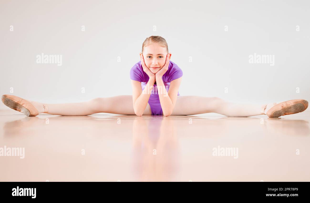 Spero che tu danzi. Scatto di una bambina che si allunga sul pavimento in uno studio di danza. Foto Stock