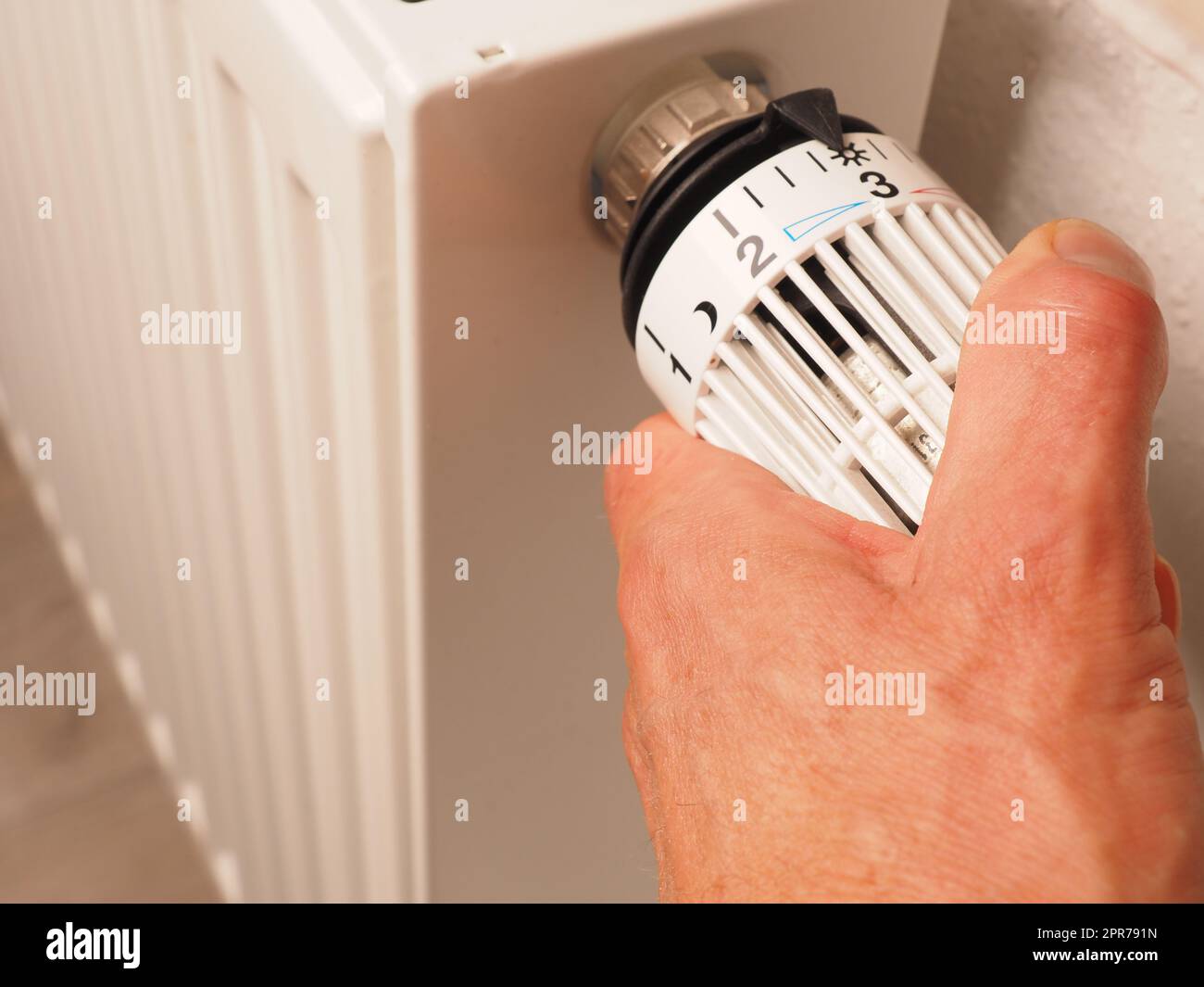 Ruota manualmente il termostato di un radiatore, risparmia energia e riduce i costi energetici Foto Stock