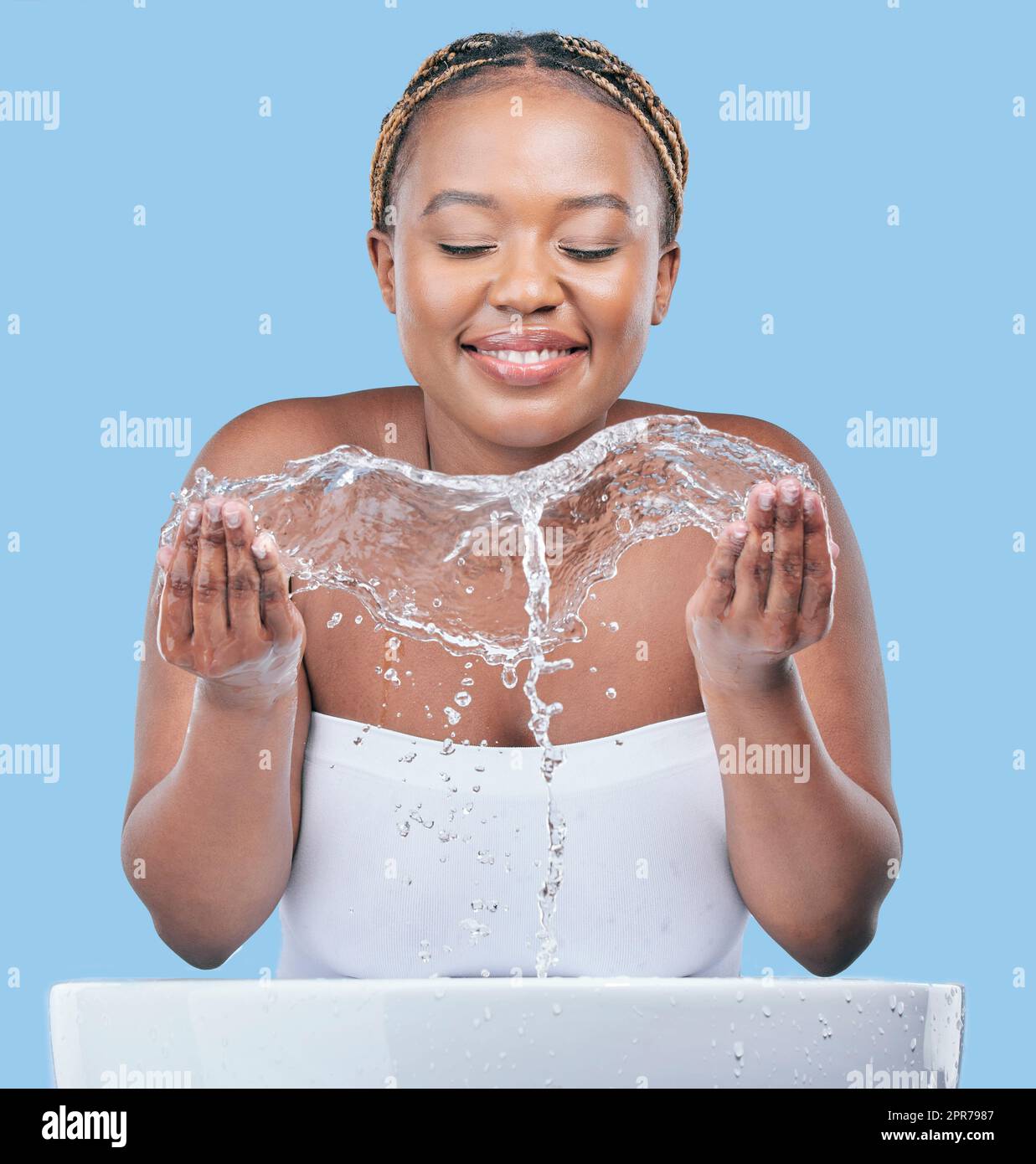 La vostra pelle avrà sempre bisogno di umidità. Studio girato di una giovane donna attraente lavando il suo viso su uno sfondo blu. Foto Stock