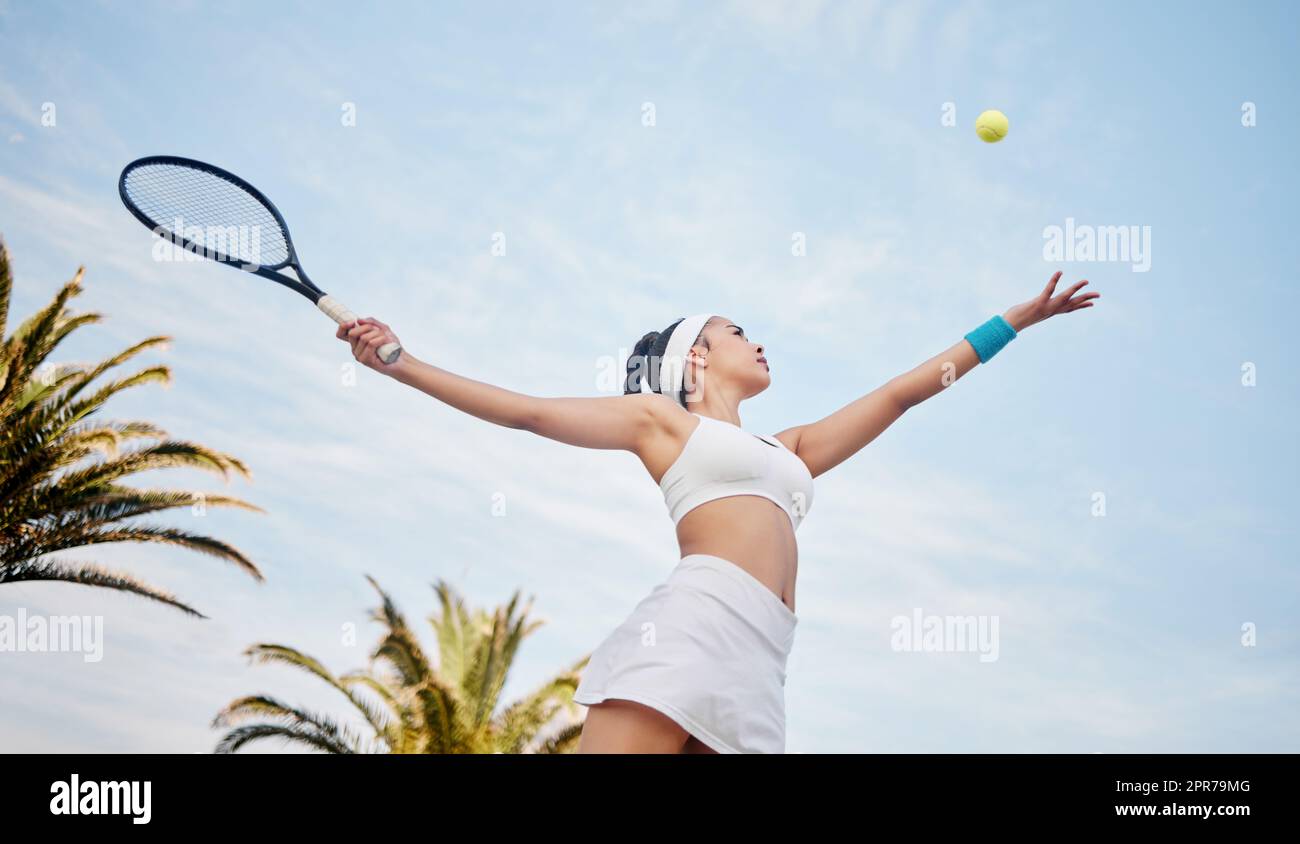 Mi rivolgo sempre al cielo. Tiro ad angolo basso di un giovane giocatore di tennis in piedi da solo sul campo e servendo la palla durante la pratica. Foto Stock