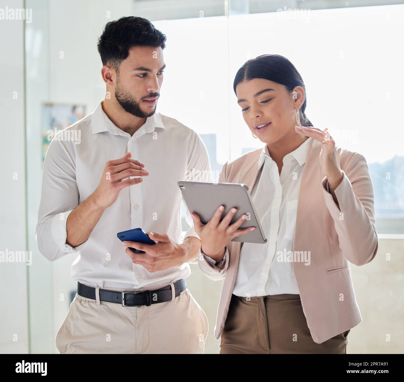 Due giovani uomini d'affari che guardano un tablet mentre si trovano in ufficio. Foto Stock