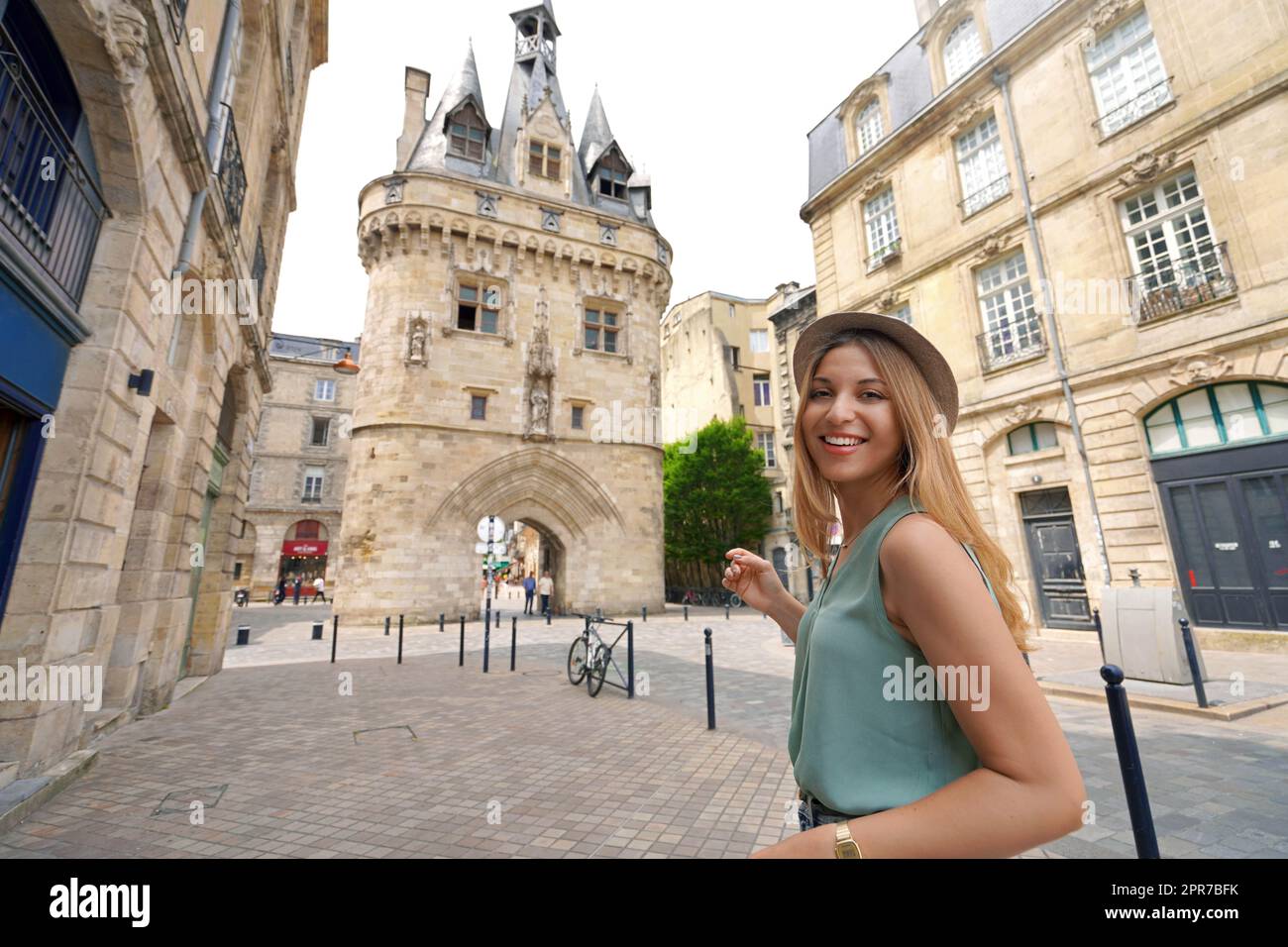 Bellissima ragazza turistica che visita la città di Bordeaux, in Francia. Donna attraente che guarda la macchina fotografica con porta fortificata porte Cailhau a Bordeaux, Francia. Foto Stock