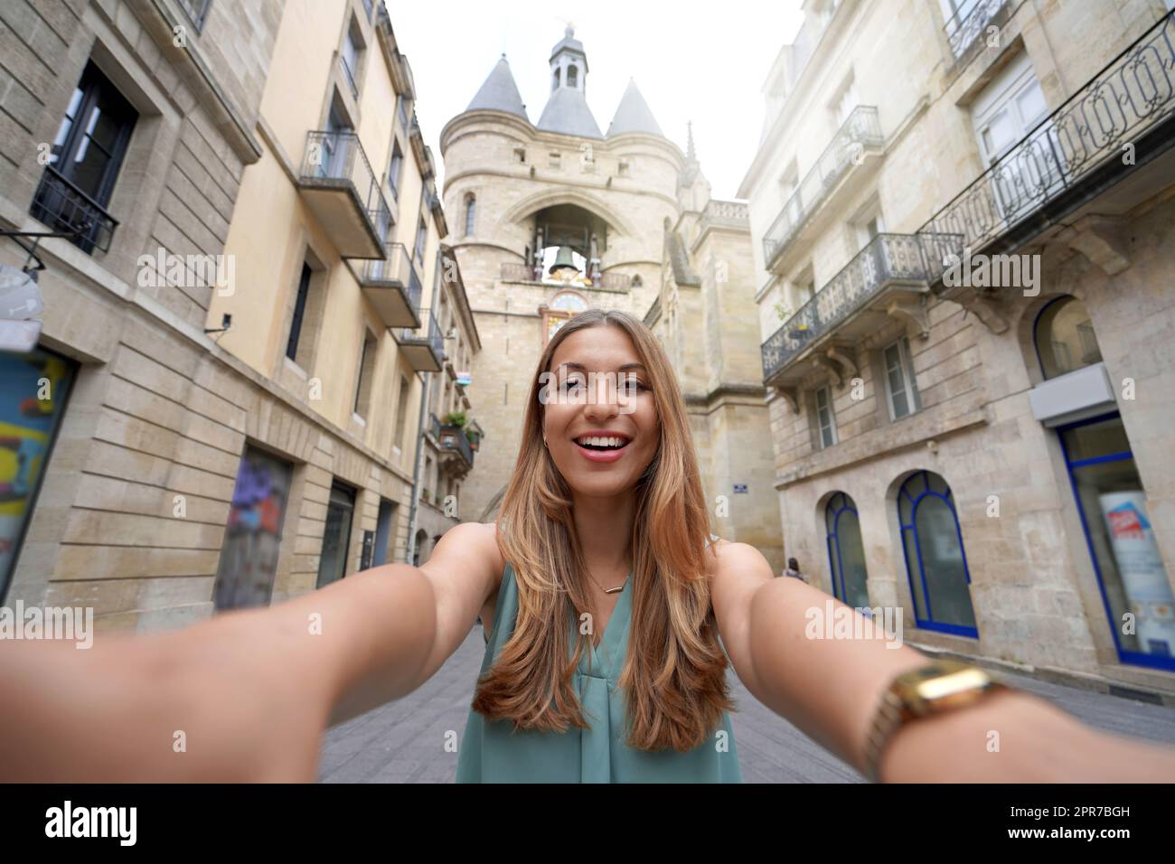 Autoritratto di giovane donna turistica sorridente a macchina fotografica con la Grosse cloche storico campanile a Bordeaux, Francia Foto Stock