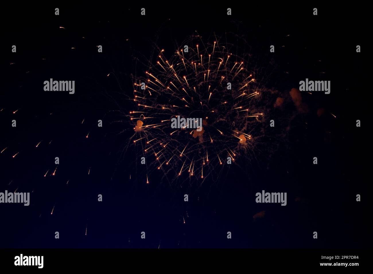 Una brillante palla di fuochi d'artificio con scintille arancioni e molte scintille sullo sfondo del cielo notturno Foto Stock