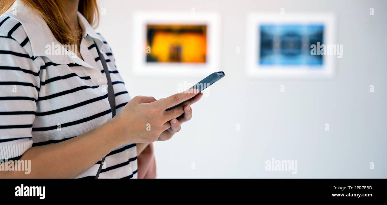 La donna asiatica in piedi scatta foto della galleria d'arte davanti a quadri incorniciati Foto Stock