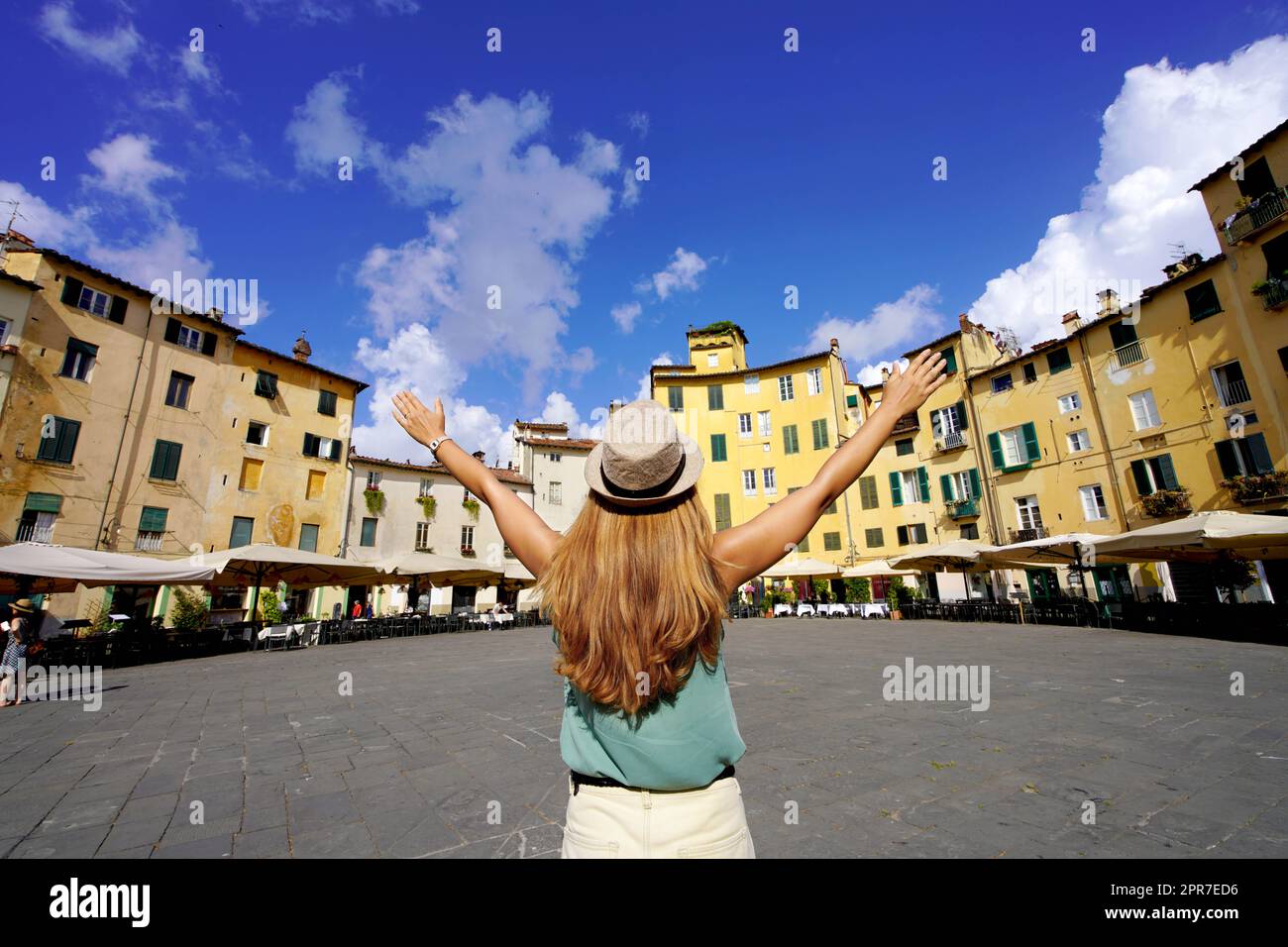 Vacanze in Toscana. Giovane donna turistica che alza le armi nella storica piazza rotonda Piazza Anfiteatro a Lucca, Toscana, Italia. Foto Stock