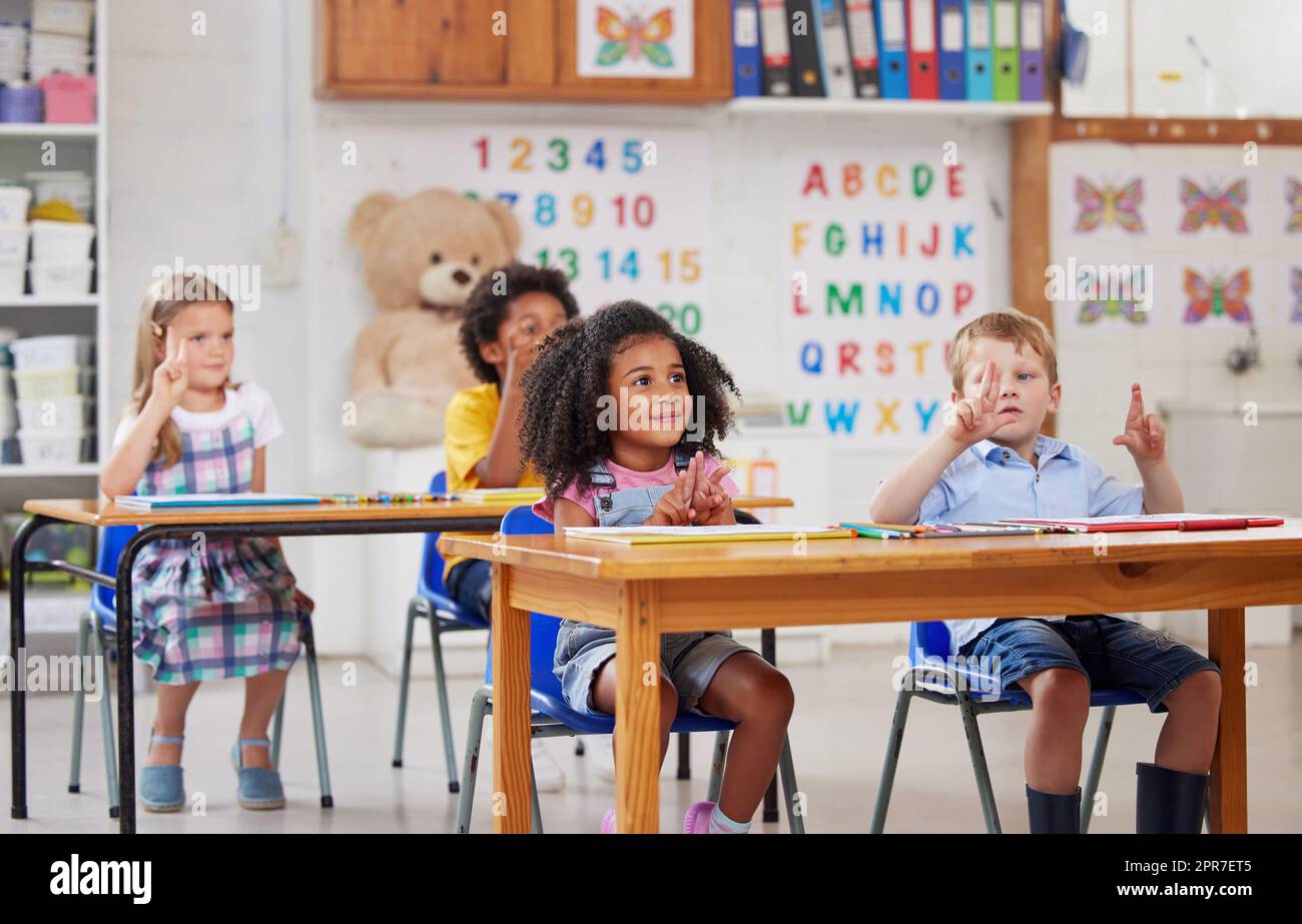 Con il preschool, il vostro bambino ottiene un inizio della testa. Shot di un gruppo di studenti prescolare seduti in un'aula. Foto Stock