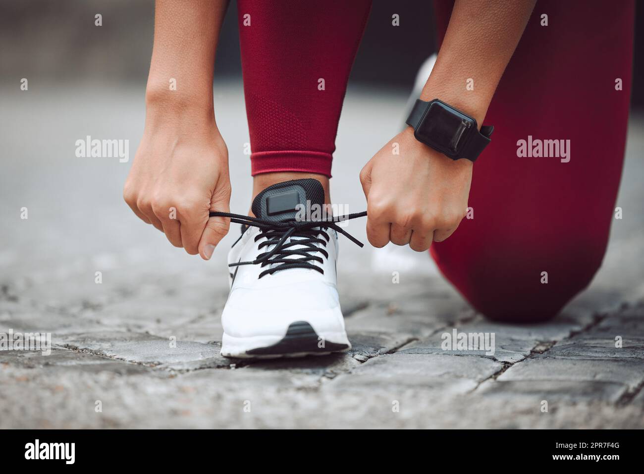 Tenendolo stretto. Un'atleta femminile irriconoscibile che lega i suoi lacci mentre corre all'aperto. Foto Stock