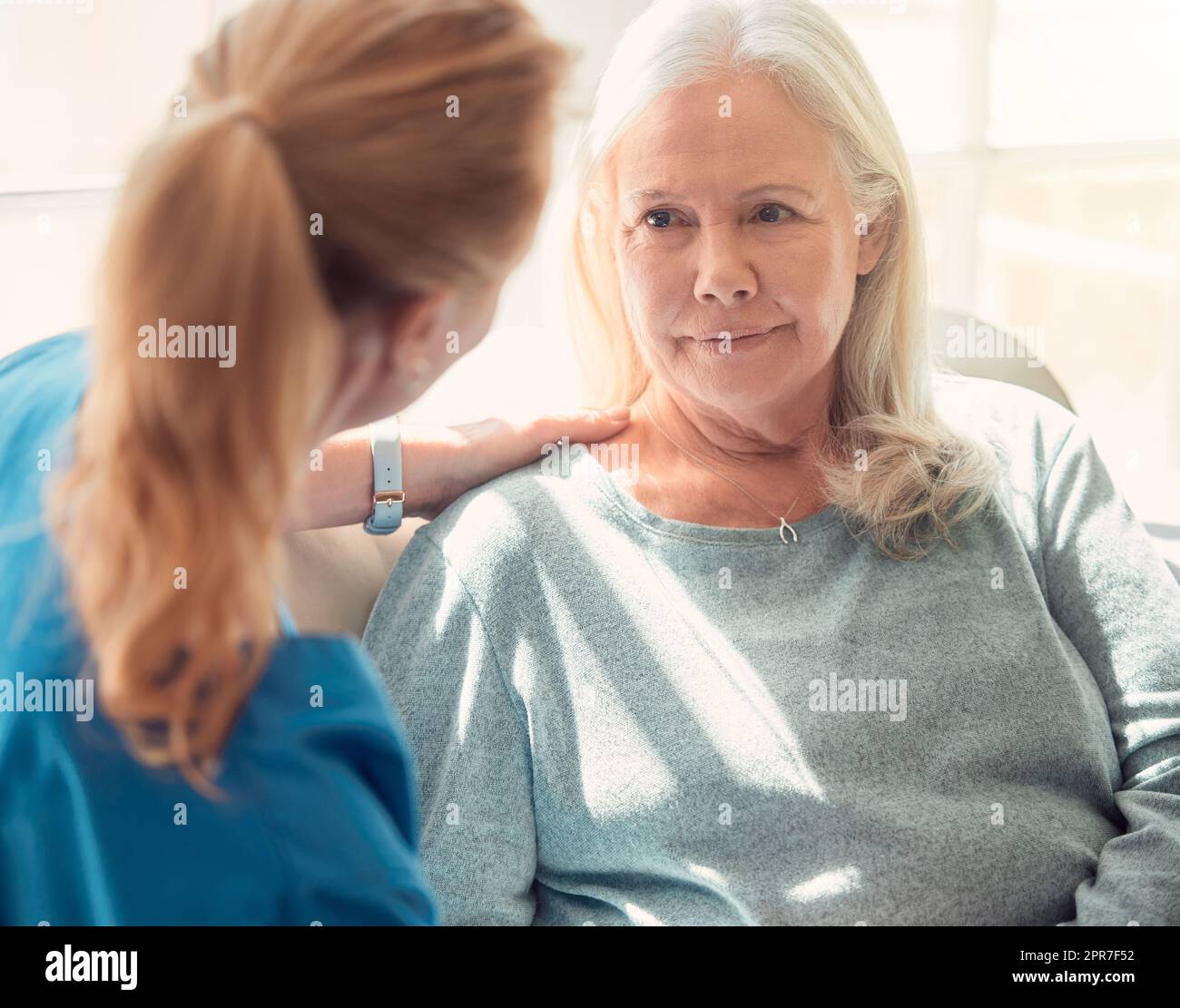 Aiutare gli altri a ottenere ciò di cui hanno bisogno. Shot di una donna anziana sostenuta dalla sua infermiera a casa. Foto Stock