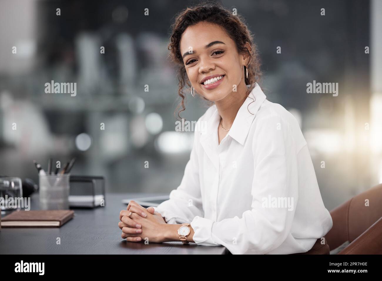 Come posso fare la vostra giornata: Una giovane donna d'affari seduta alla sua scrivania. Foto Stock