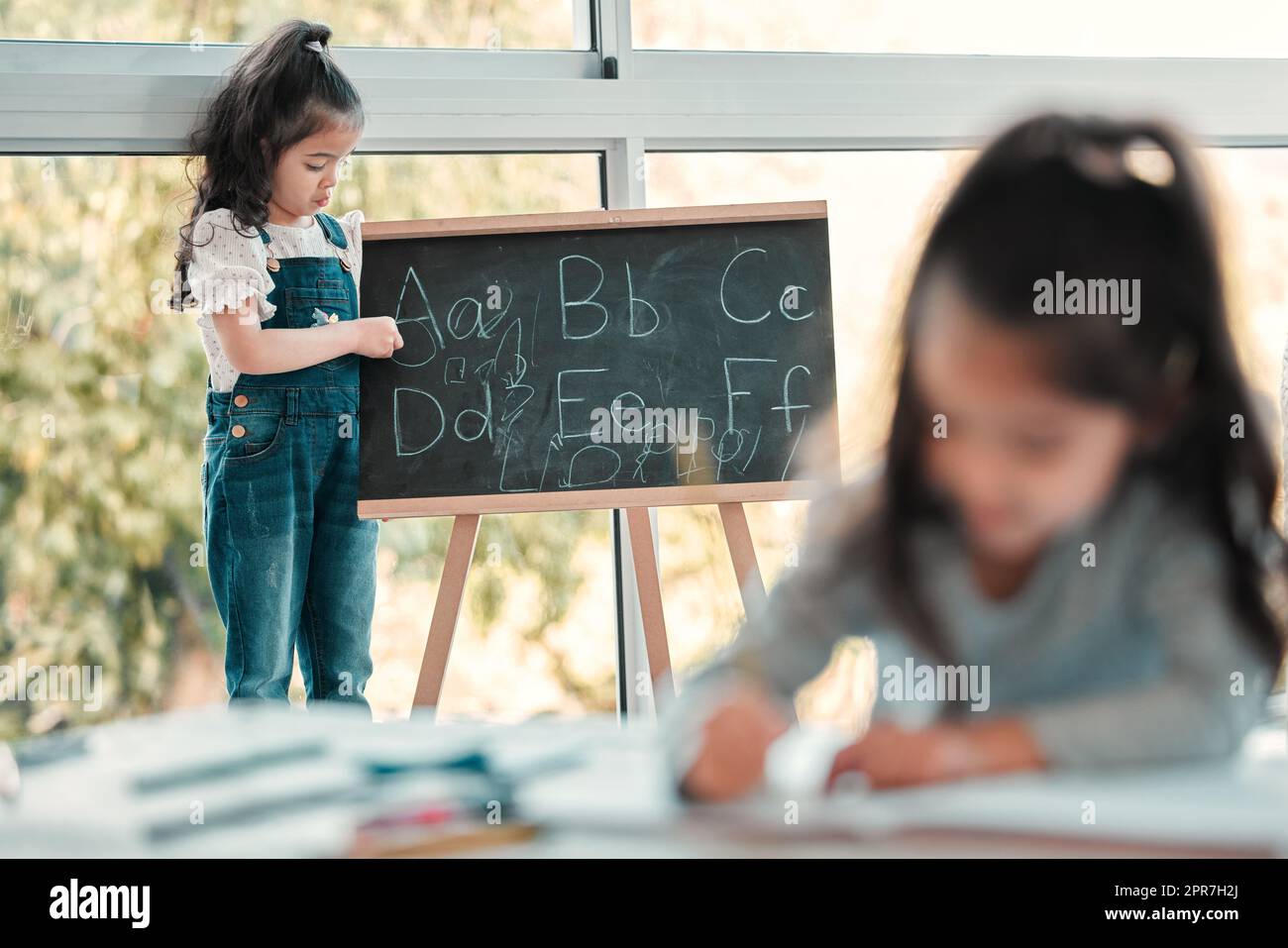 Lascia riorganizzare l'alfabeto. Una ragazza giovane che scrive su una lavagna. Foto Stock