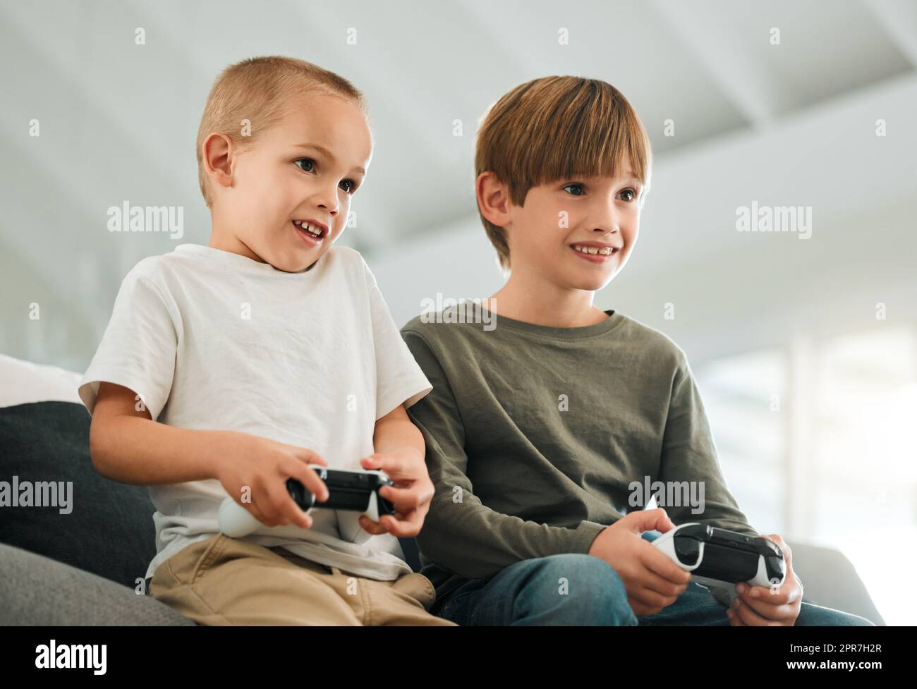 Amano giocare ai videogiochi. Due piccoli fratelli che giocano a casa. Foto Stock