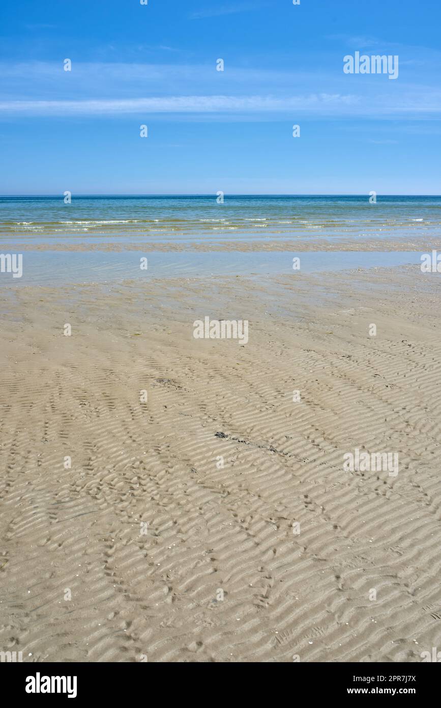 Splendido paesaggio della spiaggia con un cielo blu e spazio copia in una giornata estiva. Tranquilla e panoramica vista sull'oceano o sulla sabbia in un pomeriggio di sole. Il mare tranquillo all'aperto nella natura Foto Stock