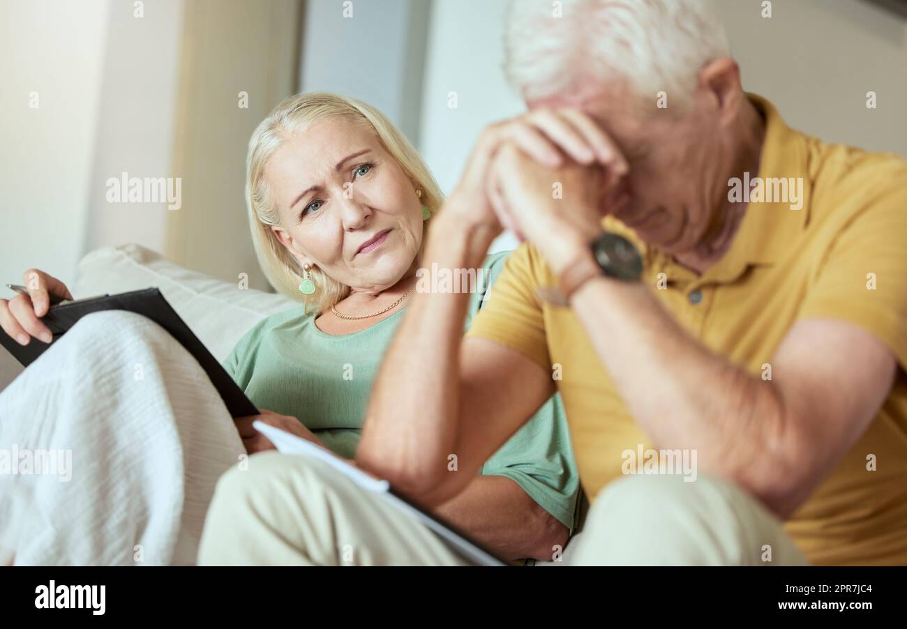 Una coppia anziana infelice seduta su un divano e sembrava stressata. Uomo e donna caucasici anziani che guardano preoccupati per il loro futuro mentre guardano i documenti e il loro debito Foto Stock