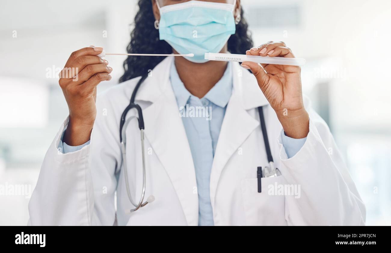 Closeup medico donna afroamericana che indossa una maschera e tiene un test del tampone in ospedale. Test per la pandemia del corona virus. Fermare la diffusione della covid 19 e fare i test. Salute e medicina Foto Stock