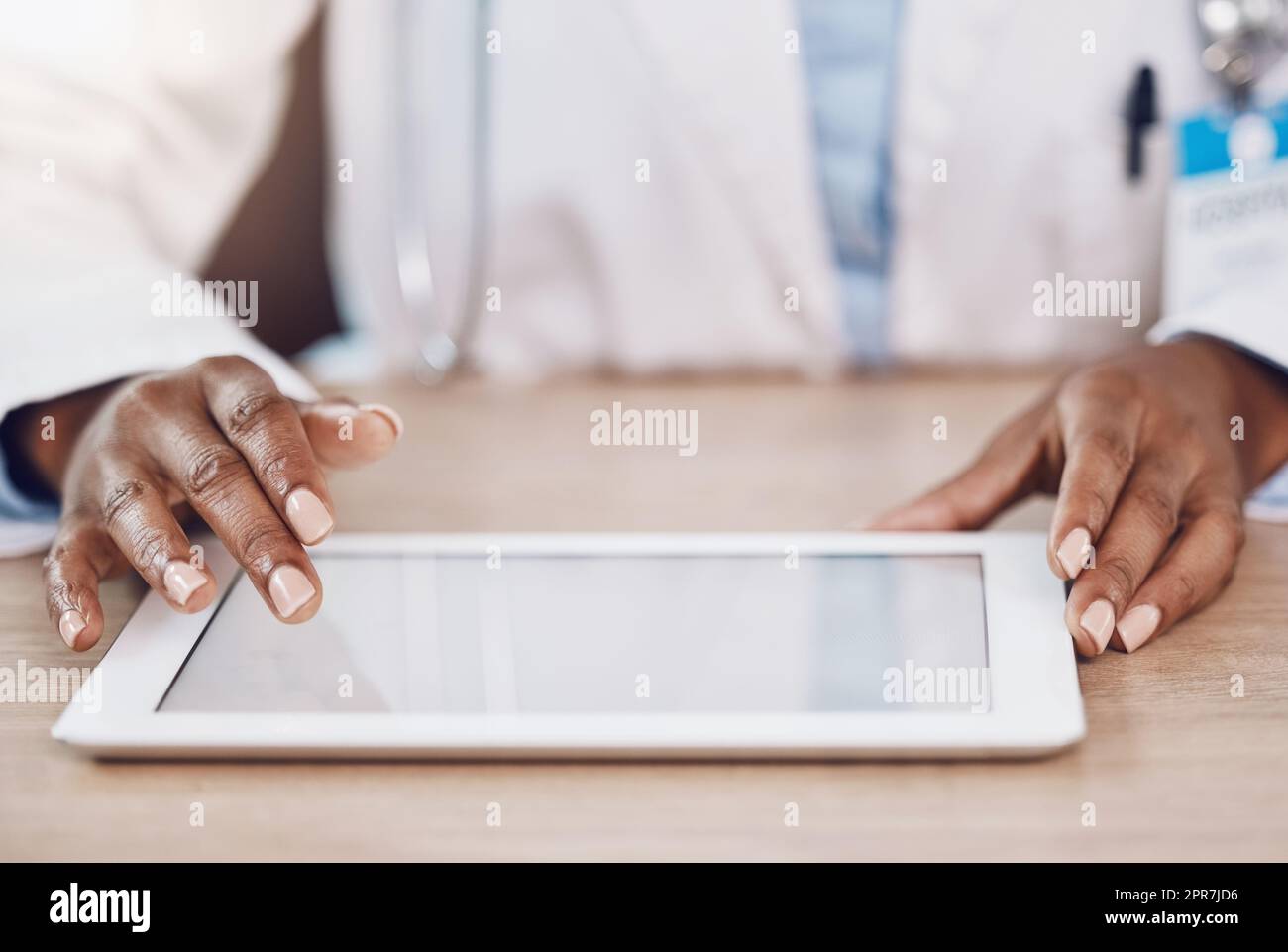 Sopra primo piano medico donna afroamericana che utilizza un tablet digitale mentre lavora presso una scrivania nel suo ufficio ospedaliero. Utilizzare la tecnologia wireless per diagnosticare le malattie nel campo della salute e della medicina Foto Stock