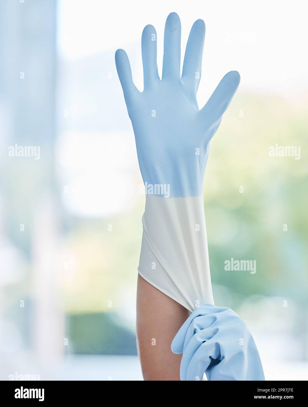 Un lavoratore domestico inriconoscibile che indossa guanti di gomma sul posto di lavoro. Una donna sconosciuta di razza mista che si prepara a fare lavori domestici Foto Stock