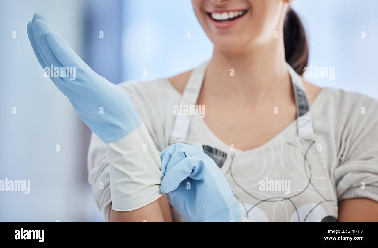 Un lavoratore domestico inriconoscibile che indossa guanti di gomma sul posto di lavoro. Una donna sconosciuta di razza mista che si prepara a fare lavori domestici Foto Stock